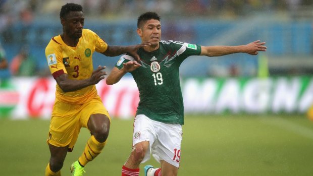  Nicolas N'Koulou of Cameroon challenges goal-scorer Oribe Peralta of Mexico.