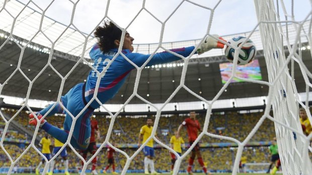 Top form: Guillermo Ochoa makes a diving save for Mexico against Brazil.