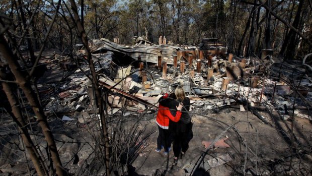 Amy Hubbard and her mum, Catherine, survey the ruins of the Winmalee home after it was destroyed during the October 2013 bushfire.