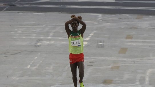 Moment of protest: Ethiopia's Feyisa Lilesa crosses his arms as he crosses the finish line.