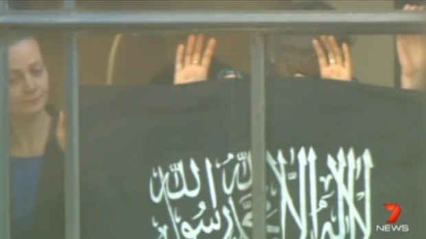 "One of the hardest things to see": Hostages, including 43-year-old Ms Mikhael, far left, hold the flag against the window.