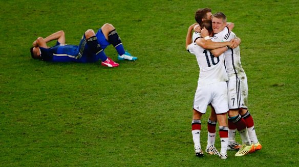 Germany celebrate as a a dejected Sergio Aguero of Argentina lies on the pitch.