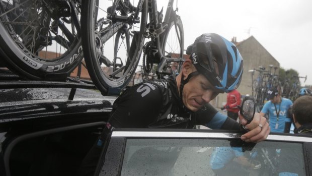 Chris Froome gets into his team's car after crashing.