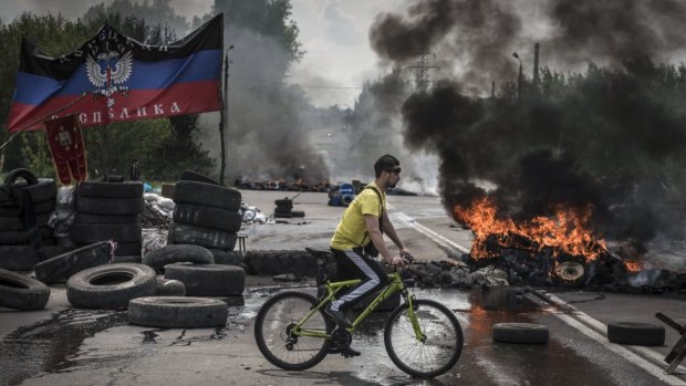Dark days: a cyclist navigates a pro-Russian checkpoint left burning by Ukrainian troops advancing on the town of Kramatorsk in eastern Ukraine.