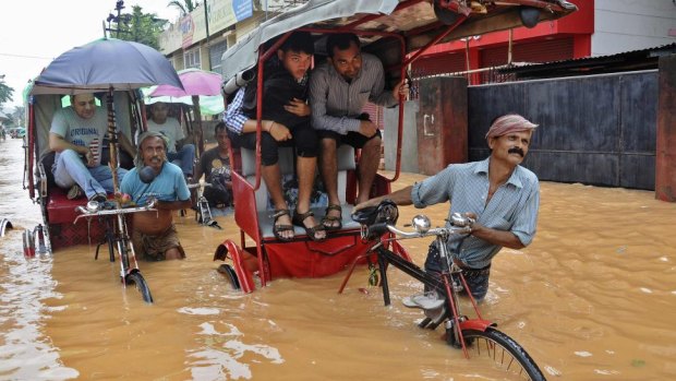 Monsoon rains leave towns flooded: Rickshaw pullers wade through a flooded road after heavy rains at Guwahati in northeastern Indian.