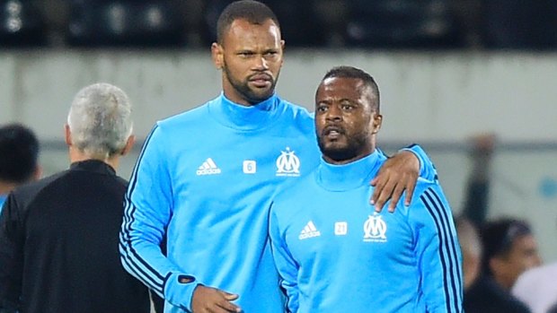 Marseille's Patrice Evra (right) is led away by teammate Rolando.