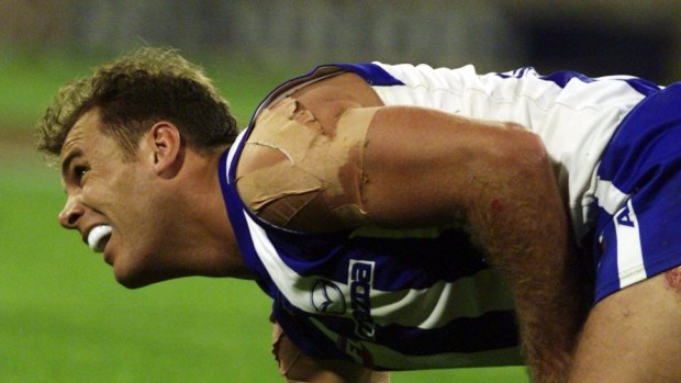 Wayne Carey winces in pain from a shoulder injury. He played on.