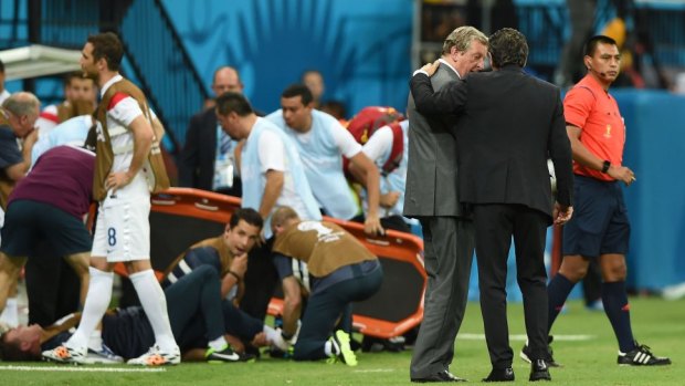 England manager Roy Hodgson speaks to head coach Cesare Prandelli of Italy as England trainer Gary Lewin lies on the ground being treated.