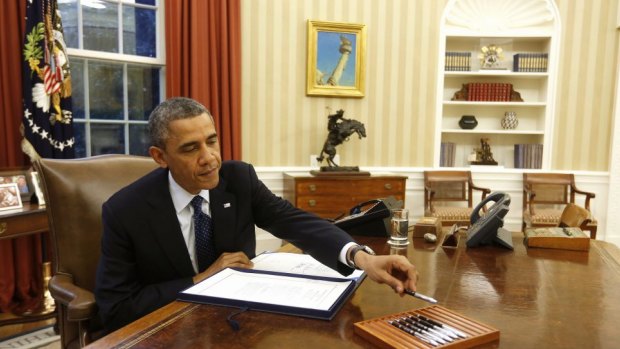 US President Barack Obama reaches for a pen as he signs a bill in the Oval Office in 2013.