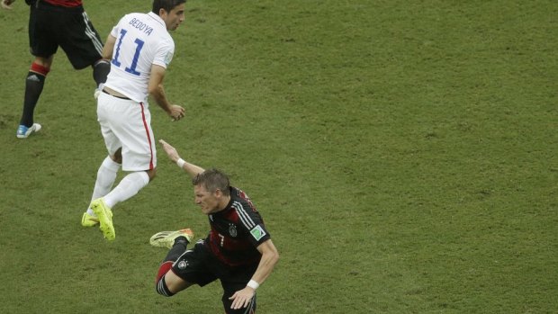 Germany's Bastian Schweinsteiger takes a tumble after a challenge by United States' Alejandro Bedoya.