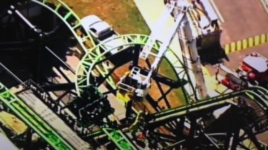 Firefighters use a cherry picker to rescue people stranded on the Green Lantern ride at Movie World.