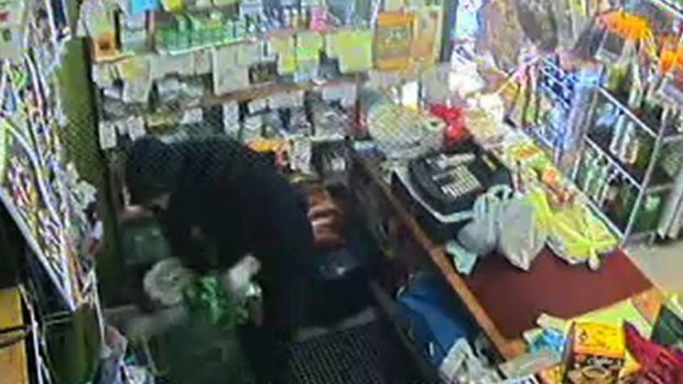 A security camera captured one of the thieves stealing cash from behind the counter.