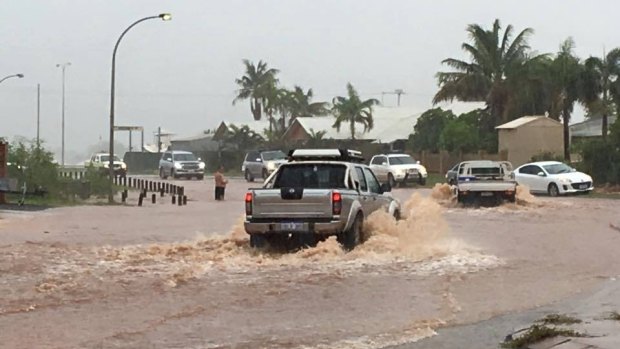 A lone man stands half-submerged in water to help traffic through the flood waters. 