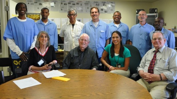 UC Berkeley Professor William Drummond (with glasses standing in centre) at the offices of the San Quentin News with inmate editors (standing) and (seated) civilian advisers. 