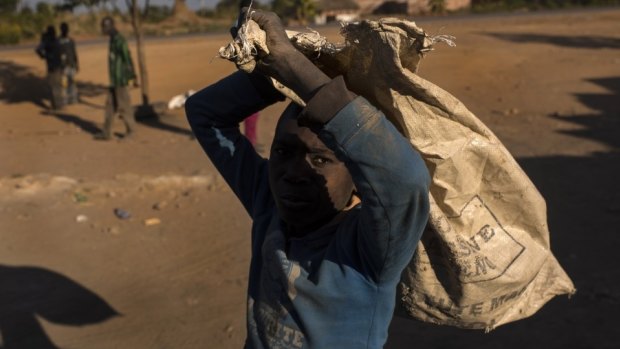 A boy carries a bag used to transport cobalt-laden dirt and rock at a mineral market outside Kolwezi, Congo.