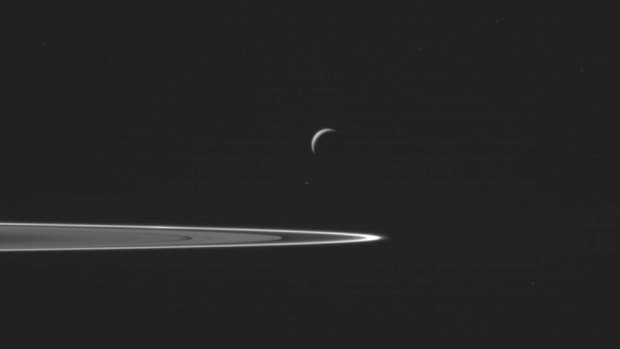 Saturn's moon Enceladus, centre, as the Cassini spacecraft prepared to make a close flyby of the icy moon. 