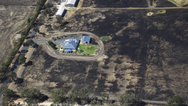 A property lies seemingly untouched, despite the burnt area of land around it.