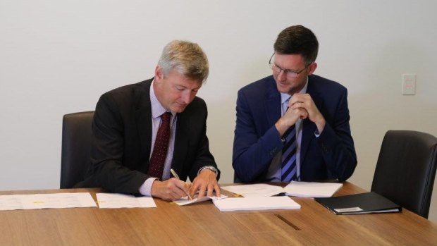 Genex executive director Simon Kidston and Energy Minister Mark Bailey sign the Palaszczuk government's first Solar 150 formal deed of agreement.