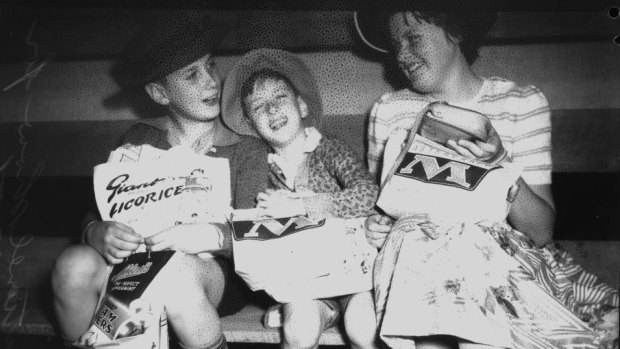 Three children enjoying their sample bags at the Ekka in 1956.