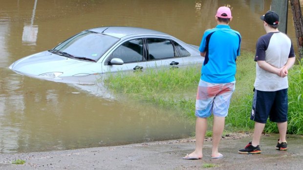 A car is trapped in a flooded street.