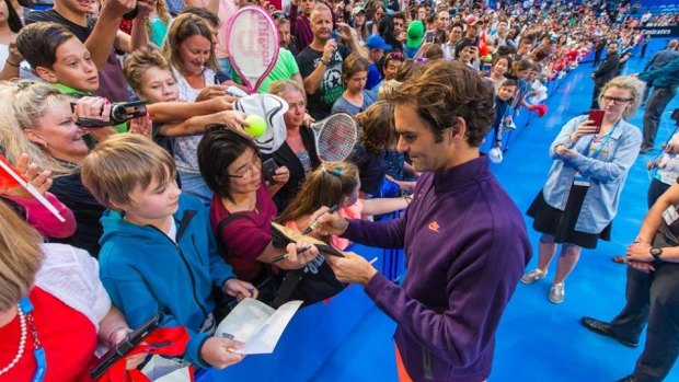 Roger Federer signs autographs for fans after a training session in Perth.