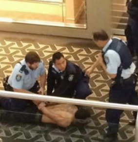 Restrained: Police subdue a man, 33, after a stabbing death at Westfield Parramatta.