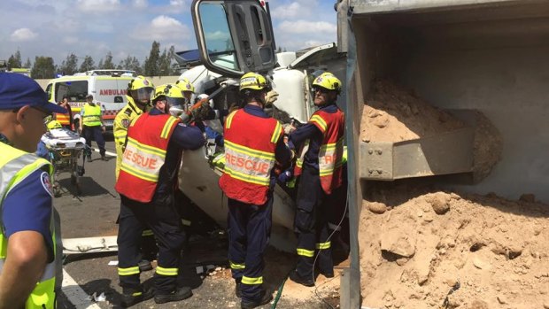 Firefighters work to free a trapped truck driver on the M7.
