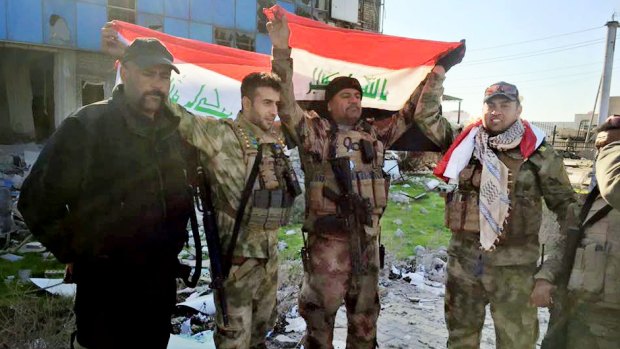 Iraqi soldiers hold national flags in the government complex in central Ramadi.