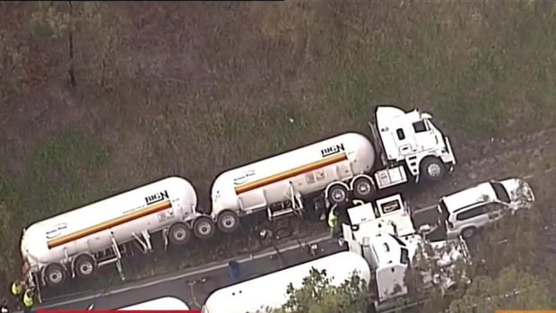 Emergency crews transfer a dangerous chemical from one truck to another after a crash on the Cunningham Highway.