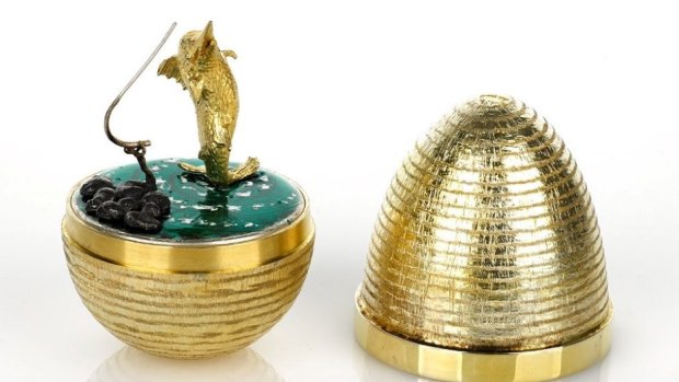 Stuart Devlin's silver gilt egg, London 1985, with textured exterior surface and polished band, opening to reveal a fisherman with a marlin on a line, set on green enamel base.
