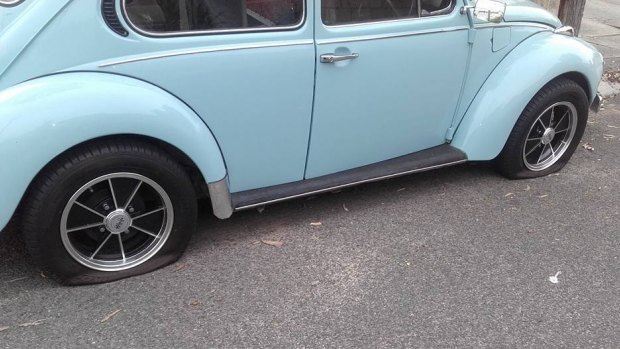 A Volkswagen Beetle with two slashed tyres.