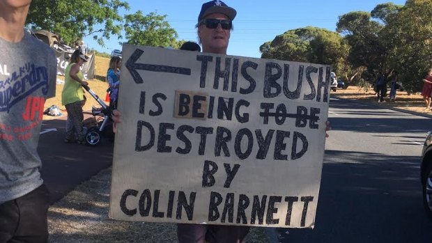 A protester holds a sign at the Roe 8 project on Tuesday.