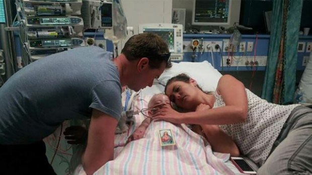 Naomi and Grant Day lying on a hospital bed with six-month-old Kyran.