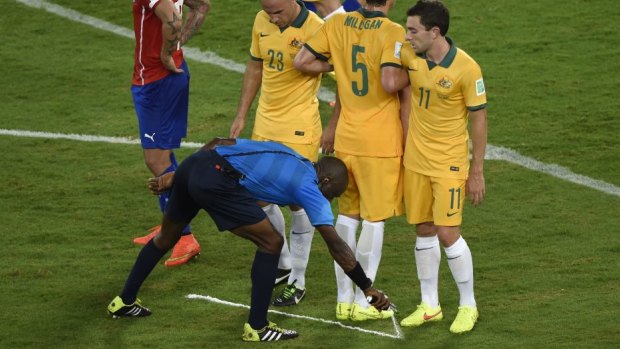 Ivorian referee Noumandiez Desire Doue uses his free-kick spray marker during the match between Chile and Australia.