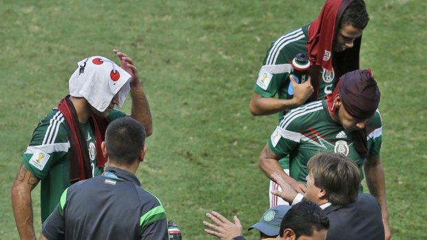 Mexico's head coach Miguel Herrera talks to his players during a cooling break.
