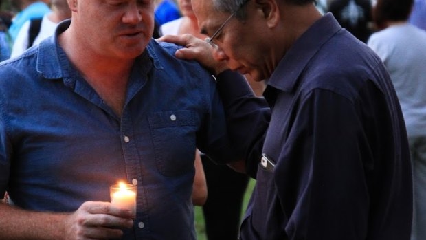 New Hope Community Church pastor Robert Chua comforts a well wisher at a candelight vigil for Queenie Xu in a park across the road from where she was stabbed to death in Parkinson.