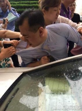 Fanya Metals Exchange boss Shan Jiuliang is bundled into a car.