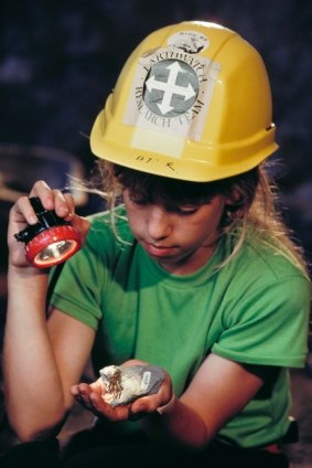 A young Leaellyn Rich holds part of the skull of a dinosaur named after her, in the mine tunnel at Dinosaur Cove, Cape Otway.