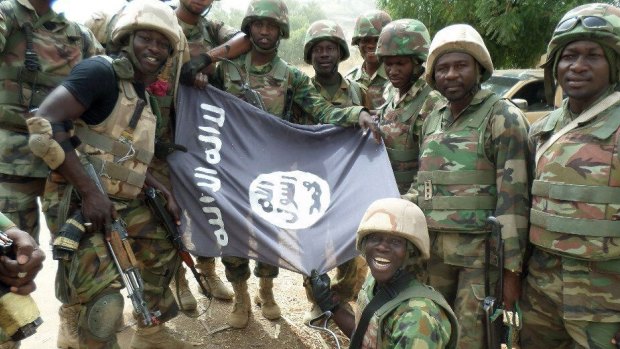 The Nigerian military pose with a flag of Boko Haram earlier this year.