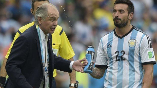 All forgotten: Ezequiel Lavezzi sprays water at coach Alejandro Sabella.