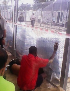 Two men reach for bottled water after the detainees blocked the compound gate.