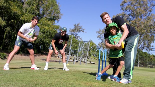 Carlin Renoug, 8, from Cherbourg gets some cricketing tips from cricketers James Faulkner, Moises Henriques and Pat Cummins at Allan Border Field, Albion. 