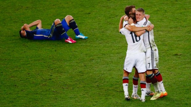 Germany celebrate as a a dejected Sergio Aguero of Argentina lies on the pitch.