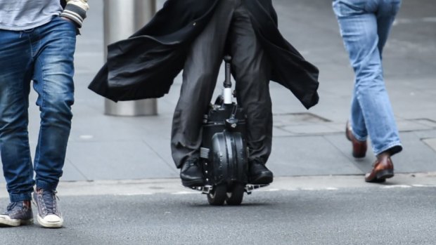  A man rides his airwheel through the streets of Sydney.
