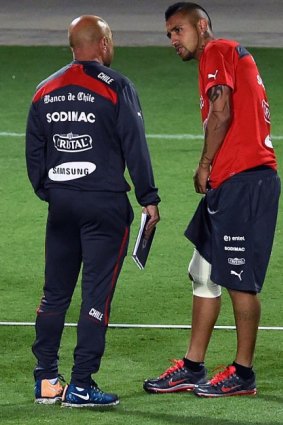 Chilean star Arturo Vidal, his right knee heavily strapped, talks to team coach Jorge Sampaoli during a training session in Belo Horizonte, Brazil.