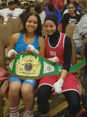 Aliyah Charbonier (L) presenting Amaiya Zafar (R) with the belt she was awarded after Zafar was disqualified from their fight for wearing a hijab.