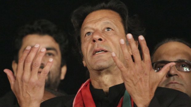 Politician Imran Khan, center, leader of Pakistan Tehreek-e-Insaf party, prays with his aides for the victims killed in Tuesday's Taliban attack.