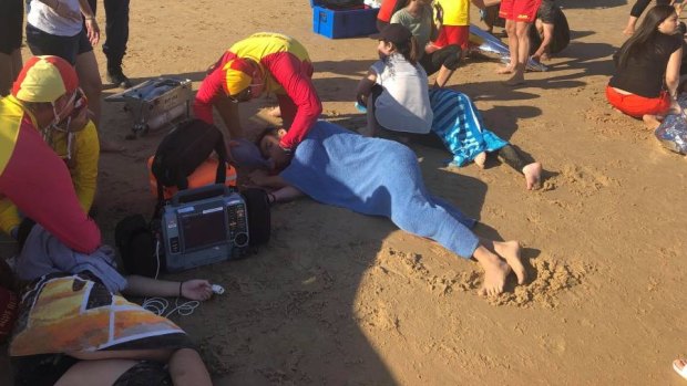 Birubi Point Surf Life Saving Club members and NSW Ambulance paramedics treating the swimmers at Birubi Beach.