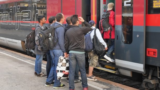 Migrants and refugees board a train in Vienna.