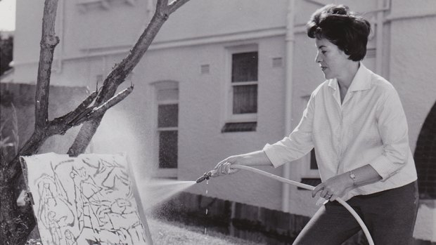 Artist Judy Cassab washing a painting with a hose in 1955.